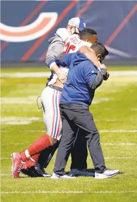  ?? ARBOGAST/APPHOTO CHARLES REX ?? NewYork Giants running back Saquon Barkley is helped off the field after being injured against the Chicago Bears during the first half in Chicago on Sunday.