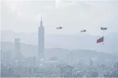  ?? NYT ?? Taiwanese helicopter­s fly the country’s flag through downtown Taipei on Oct 5.