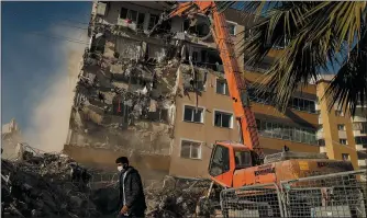  ?? PHOTOS BY EMRAH GUREL — THE ASSOCIATED PRESS ?? A worker walks past as others demolish a building that was damaged at the Oct. 30 earthquake in Izmir, Turkey, Wednesday. Search and rescue operations for survivors had been completed Wednesday at several buildings that fell in the coastal city. More that a hundred people were killed and more that a thousand people were injured.