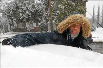  ?? PETE BANNAN – DIGITAL FIRST MEDIA ?? Erik Lewis clears snow from the roof of his new car in Drexel Hill Wednesday. He wanted to get it off the road due to the snow emergency.