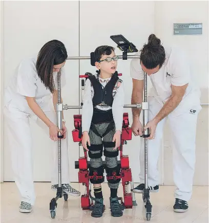  ?? ?? Raúl, de 10 años, junto al equipo sanitario que le coloca el exoesquele­to y registra sus avances