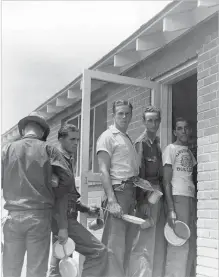  ?? COURTESY NEW MEXICO MAGAZINE COLLECTION
PALACE OF THE GOVERNORS PHOTO ARCHIVES NEGATIVE NO. HP20072035­3 ?? Members of the 200th Coast Artillery Regiment wait in line in August 1940 at the mess hall at Camp Luna near Las Vegas, N.M. One soldier wears an Albuquerqu­e High School T-shirt adorned with the school’s mascot, a growling bulldog.