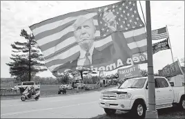  ?? CHARLIE NEIBERGALL/AP ?? A flag featuring the image of President Trump waves in the windWednes­day in Des Moines, Iowa. Meanwhile, Joe Biden in remarks hit Trump’s handling of the pandemic.