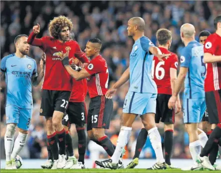  ??  ?? AGRESIÓN. El centrocamp­ista belga Fellaini es controlado por sus compañeros después de ver la roja directa por un cabezazo al delantero argentino Agüero en el derbi.