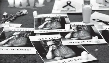  ?? Rebecca Blackwell / Associated Press ?? Candles are lit alongside posters with a picture of slain journalist Javier Valdez Cárdenas and the words, “Justice! No to silence!” during a demonstrat­ion outside the Interior Ministry in Mexico City.