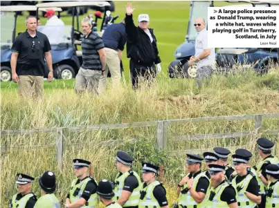  ?? Leon Neal ?? &gt; A large police presence as Donald Trump, wearing a white hat, waves while playing golf in Turnberry, Scotland, in July