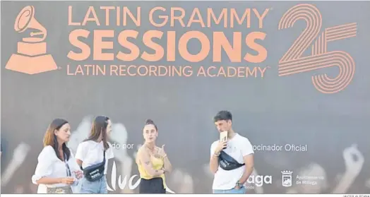  ?? JAVIER ALBIANA ?? Jóvenes junto a un cartel que anuncialos Latin Grammys en la plaza de toros e La Malagueta.