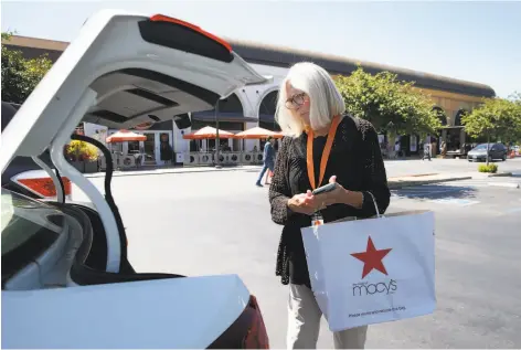  ?? Photos by Paul Chinn / The Chronicle ?? Lynne Richardson, a driver for Deliv, picks up items at Stanford Shopping Center ordered through the Macy’s website for delivery.