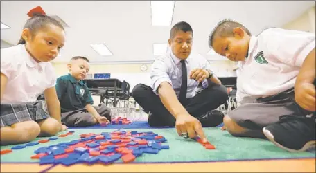  ?? Al Seib Los Angeles Times ?? RUBEN ALONZO, founder of Excelencia Charter, works with kindergart­ners Darlene Morales, Azariah Terrazas and Adrian Vargas.