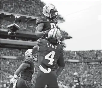  ?? LINDSEY WASSON/AP PHOTO ?? Washington wide receiver Giles Jackson, top, is lifted up by Germie Bernard (4) after scoring a touchdown the No. 7 Huskies’ 36-33 win over No. 8 Oregon on Saturday in Seattle.