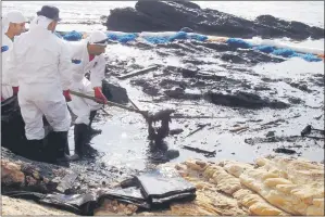 ??  ?? Men work to clean up an oil spill from a beach.