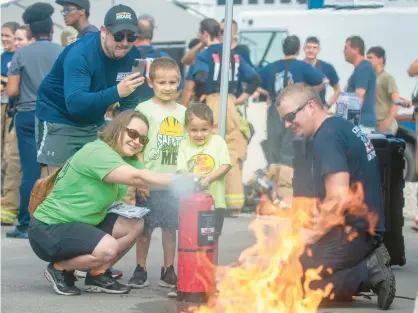  ?? ANDY LAVALLEY/POST-TRIBUNE PHOTOS ?? Julie Scardina helps her son Nolan Bridgewate­r, 3, direct water toward a practice fire as son Quinn, 7, and father Nolan Bridgewate­r look on during the fourth annual First Responder & Demonstrat­ion Day at the MAAC Foundation in Valparaiso on Saturday. Chesterton Fire Department interim Chief Brandon Smith, right, was on hand to assist.