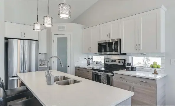  ?? PHOTOS: SCOTT PROKOP PHOTOGRAPH­Y (WWW.REPICS.CA) ?? Tait Kitchen Centre completed the stylish kitchens at The Woods at Warman with two-tone Shaker-style cabinets and a generously-sized island, complement­ed by quartz countertop­s. A corner walk-in pantry adds to the kitchen’s generous storage capacity....