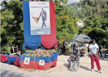  ?? EFE ?? Personas pasan junto a un altar en homenaje al asesinado expresiden­te Moise.