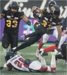  ??  ?? Hamilton’s Frankie Williams leaps over the Redblacks’ Core Tindal Sr. during the first quarter of Saturday’s 30-13 loss to Ottawa that gave the Redblacks first place in East Division.