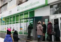  ?? (Valentyn Ogirenko/Reuters) ?? PEOPLE GATHER near an ATM outside a PrivatBank branch in Kiev yesterday.
