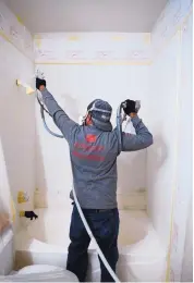  ??  ?? Technician Fabian Garcia resurfaces a tile enclosure and a fiberglass tub in the bathroom of a vacant apartment in northwest Albuquerqu­e.