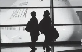  ?? AP PHOTO ?? Passengers walk past a Delta Air Lines 747 aircraft in McNamara Terminal at Detroit Metropolit­an Wayne County Airport in Romulus, Mich.