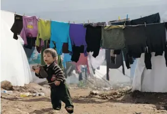  ?? Hussein Malla/the Associated Press ?? A Syrian refugee child walks between tents at Atmeh refugee camp, in the northern Syrian province of Idlib in February. The number of child refugees fleeing the war-torn country has topped one million.