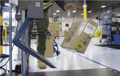  ?? ELLEN M. BANNER/THE SEATTLE TIMES/TNS ?? Dominic Williams Shepperd, a lab tech in Amazon’s sustainabl­e packaging lab in Sumner, uses a drop tester in May to check the durability of the packaging. He drops the box nine times, then takes it to sit on the vibration table for three hours and then drops it eight more times before opening the box to see if the merchandis­e inside the box has been damaged. The box hits every possible edge and corner as it is dropped.