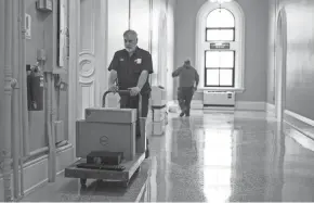  ?? TY WRIGHT/LANCASTER EAGLE-GAZETTE ?? Facility employees work Monday on the third floor of the Fairfield County Courthouse where the floor was recently refinished, along with other renovation­s.