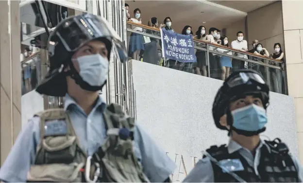  ?? PICTURE: ANTHONY KWAN/GETTY IMAGES ?? 0 Pro-democracy supporters hold a Hong Kong Independen­ce flag during a rally against the national security law as riot police stand by