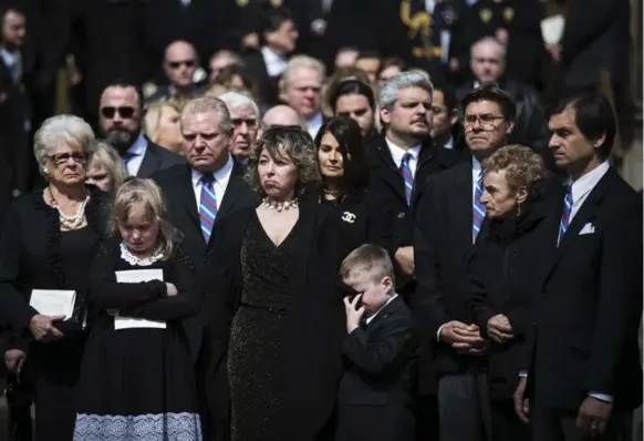  ?? MELISSA RENWICK/TORONTO STAR ?? Dougie Ford wipes away his tears with his mother Renata’s jacket after his father, Rob Ford, was farewelled at St. James Cathedral on Wednesday.