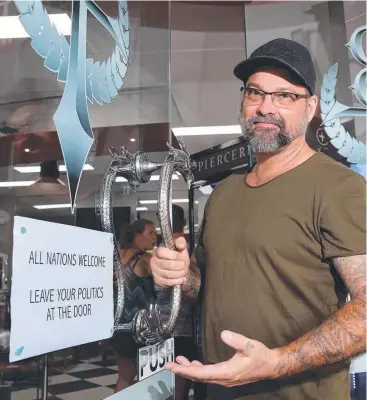  ?? Picture: ANNA ROGERS ?? COME IN: Cairns City Tattoo owner Duane Cash has put up a sign welcoming all nationalit­ies in response to a sign previously displayed at a studio in the city.