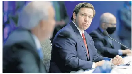  ?? WILFREDO LEE/AP ?? Gov. Ron DeSantis, center, listens as Miami-Dade County Mayor Carlos Gimenez, left, speaks during a news conference on COVID-19 June 19 at Florida Internatio­nal University in Miami. A political science professor feels DeSantis has paid a political price for being slower to lock down the state.