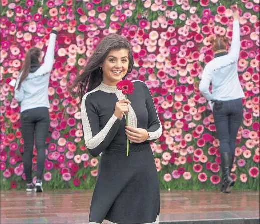  ??  ?? FLOWER POWER: Broadcaste­r Storm Huntley stands in front of a wall of flowers in Glasgow’s city centre to highlight a new drive encouragin­g women to go for their smear test. Picture: PA