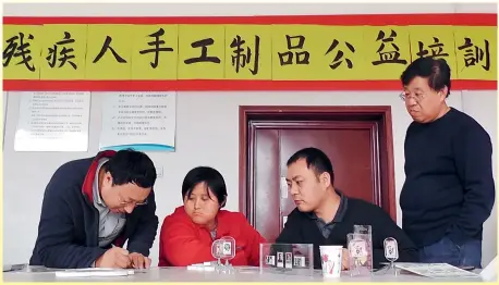  ??  ?? 王江雁（左一）为残疾人进行职业技能­培训