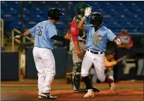  ?? DAVID C. TURBEN — FOR THE NEWS-HERALD ?? Captains second baseman Brayan Rocchio is greeted at home plate by teammate Mike Amditis (26) after Rocchio hit a two-run, game-tying home run in the bottom of the eighth inning.