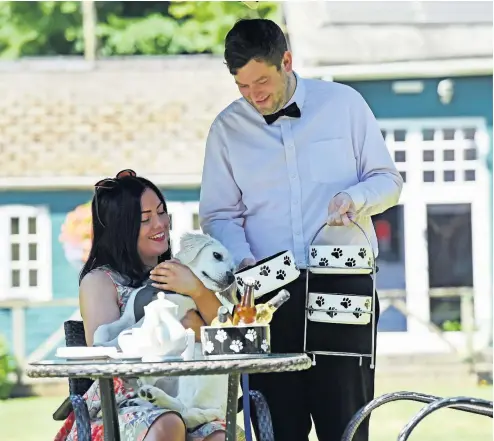  ?? RICHARD SWINGLER ?? Waiter Sion Durham serves Tyler Mears and her puppy, Atlas afternoon tea at the Coed-y-Mwstwr Hotel in Bridgend