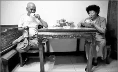  ??  ?? Li (L) and his wife Liang Xiaoyan drink tea at their apartment.