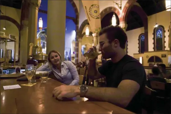  ?? DAKE KANG — THE ASSOCIATED PRESS ?? Jesse Hulien, right, drinks a beer as Molly Hartman, left, looks on, at the Church Brew Works, a former church renovated into a brewery, in Pittsburgh. Breweries opening in renovated churches are winning fans but earning disapprova­l from clergy and...