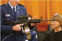  ?? Associated Press ?? ■ Police Sr. Sgt. Paddy Hannan shows New Zealand lawmakers an AR-15 style rifle April 2 in Wellington, New Zealand. The rifle is similar to one of the weapons a gunman used to slaughter 50 people at two mosques. Dozens of Christchur­ch gun owners handed over their weapons in exchange for cash in the first of more than 250 planned buyback events around New Zealand after the government outlawed many types of semi-automatics.