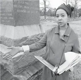  ?? STEVE HELBER/AP ?? Nadia Orton, a genealogis­t and family historian, holds research next to a monument to Black Civil War Union soldiers March 23 in Portsmouth, Virginia. Orton has worked tracing her own family and others to historical­ly Black cemeteries.