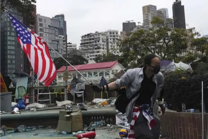  ??  ?? En demonstran­t flagger med et amerikansk flagg ved Hongkongs tekniske universite­t i går. En gruppe demonstran­ter forskanser seg fremdeles på universite­tsområdet.