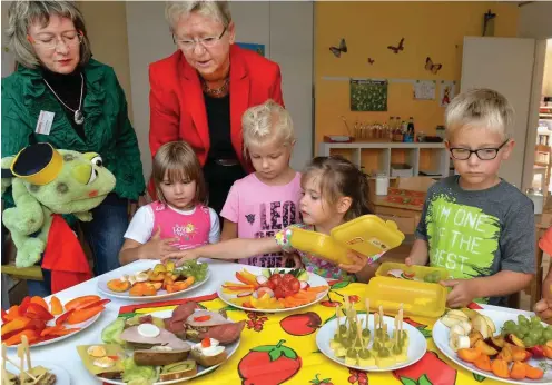  ?? Foto: dpa/Bernd Settnik ?? Anita Tack packt im August 2014 mit Ernährungs­beraterin Veronika Wrobel (l.) und Kindern in der Kita »Zwergenvil­la« in Nuthetal gesunde Brotboxen.