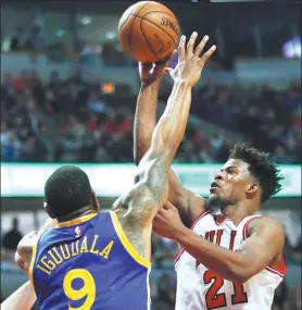  ?? NAM Y. HUH / AP ?? Chicago Bulls' Jimmy Butler gets a shot away despite Andre Iguodala’s best efforts during the Bulls’ 94-87 NBA victory over Golden State Warriors on Thursday in Chicago.