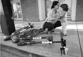  ??  ?? Siena Sarmiento speaks to her son Carter, 2, next to scooters left on an Oakland sidewalk. (Photo: San Francisco Chronicle)