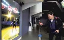  ??  ?? A man tests his table tennis skills with multimedia interactiv­e technology at the museum.