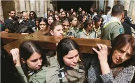  ?? GIL COHEN-MAGEN/GETTY-AFP ?? Palestinia­n Arab scouts help carry a wooden cross out of the Church of the Holy Sepulcher during the Good Friday procession in Jerusalem’s Old City.