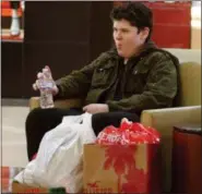  ?? JONATHAN TRESSLER — THE NEWS-HERALD ?? Geneva resident Devin Lee swallows a gulp of water Nov. 23 as he sits with a treasure trove of holiday gifts while his mom and aunt browse inside Victoria’s Secret as Thanksgivi­ng Day’s Black Thursday holiday shopping blitz commences in Mentor.