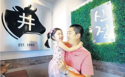  ?? JOE BURBANK/ORLANDO SENTINEL PHOTOS ?? Michael Lee, owner of Shin Jung Korean BBQ, holds 3-year-old daughter Priscilla inside his newly rebuilt restaurant Thursday. Shin Jung, a longtime staple of Korean dining in Orlando, was gutted in a June 2019 fire.
