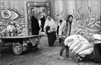  ?? ASHRAF AMRA / ASSOCIATED PRESS ?? Palestinia­n men load a horse-drawn cart with food donations outside the United Nations food distributi­on center in al-Nusirat refugee camp in the Gaza Strip on Wednesday.