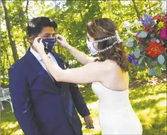  ?? Olivier Douliery / AFP via Getty Images ?? Newly married couple Rachel and Sebastian Vasquez, from Lynchburg, Va., adjust their masks for the first time as husband and wife on Saturday, after a ceremony at the Glencliff Manor in Rustburg, Va. The Glencliff Manor hosts free, socially distanced ceremonies for couples left with no wedding plans during the coronaviru­s pandemic. Only 10 people are allowed at each hourlong ceremony.