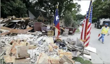  ?? DAVID J. PHILLIP — THE ASSOCIATED PRESS ?? In this Sept. 5, 2017, photo, a worker walks past a pile of debris outside a business damaged by floodwater­s in the aftermath of Hurricane Harvey in Spring, Texas. With federal disaster reserves running out, the House is swiftly moving to pass...