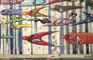  ?? Genaro Molina Los Angeles Times ?? CALIFORNIA­NS, such as this man walking past a mural by Kenny Scharf in Culver City, have been dealing with a historic heat wave. Gov. Gavin Newsom on Friday signed bills aimed at addressing extreme heat.