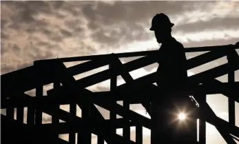  ?? AP FILE PHOTO ?? A worker climbs onto the roof of a home under constructi­on on June 20, 2017 in Phoenix, Ariz. Statistics released by the U.S. Census Bureau show women are earning more in the workplace, but men are earning less.